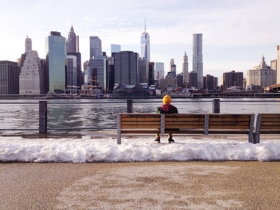 人在针织帽坐在板凳白天在身体前面的水
